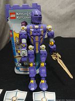 Purple Danju figure with original container and wooden sword accessory positioned upright