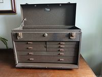 Open lid showing interior storage compartment and drawer row beneath