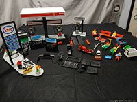 Full view of all included Playmobil Esso gas station set pieces including figures, signs, and vehicles arranged on black background.