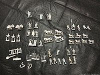 Overview of all miniatures laid out on black fabric showing figures, horses, heraldic symbols, and weapon parts.