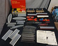 Full overview of the train set showing train cars, station buildings, track sections, roadbed pieces, and accessories.