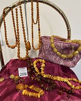 Full view of lot on burgundy fabric with necklaces draped on frame and cosmetic bag