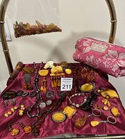 Overall display: cosmetic bag, plastic bag of loose amber, assorted jewelry on burgundy cloth