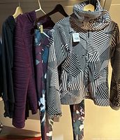View of four garments hanging: striped Bench jacket, purple Joe Fresh jacket, Capri yoga pants, black Guess top, showing colors and patterns.