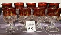 Set of 9 cranberry crystal small goblets by Indiana Glass Company displayed on a table.