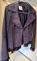 Front view of purple leather jacket showing perforated detailing and pleated trim on cuffs and hem.