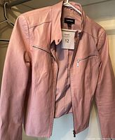 Front view of pink Danier leather jacket with zipper pockets and zipper front closure on hanger