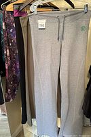 Grey Lulu yoga pants with green Lulu logo and drawstring waist displayed on hanger showing full front view with tag