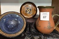 Photo showing the jug, the blue bowl, and the brown plate together on a black marble surface.