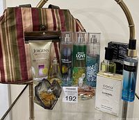 The full assortment of perfumes and toiletry bag shown on a reflective surface with all labeled bottles visible.