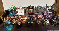 Group photo of 20 Skylanders figures showing a variety of characters, sizes, and base designs, placed on a flat surface.