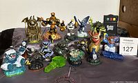 Wide shot showing 18 Skylanders figures in various sizes and designs, and the Guitar Hero toy controller.