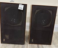 Pair of vintage KEF speakers shown front view with black mesh grilles and wood casing set side by side.