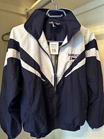 Front view of navy and white Tommy Hilfiger youth jacket with zipper and logo.