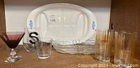 Wide shot of the CorningWare Blue Cornflower platter along with various glassware including a purple cocktail glass, a glass with an S letter, small tumblers, and the glass tri-compartment dish