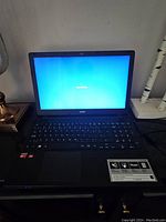 Front view of Acer Aspire E 15 laptop powered on with Windows loading screen visible.