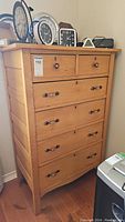 Front view showing six drawers including two smaller top drawers and four larger lower drawers, metal handles, natural pine wood finish.