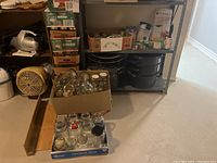 Glass canning jars boxed and on tray near shelving with canning pans and canned goods in background