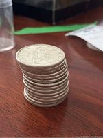 Stack of fourteen silver Canadian dollars showing reeded edges and top coin dated 1965