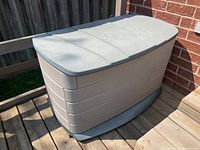 Closed Rubbermaid deck box showing beige and green textured plastic external panels.