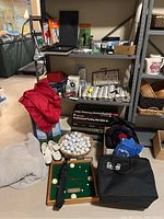 Shelf and floor display of golf balls, rain jacket, golf shoes, blanket, and wall clock among other golf-related items.