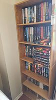 Six wooden shelves filled with hardcover novels primarily by David Baldacci, Clive Cussler, James Patterson and others