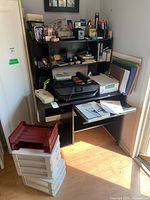 Full view of office supplies set up on dark wood desk with organizer shelves, showing HP Envy 5010 printer/scanner, paper trays stacked on floor, and assorted office supplies.