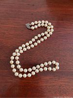 Full view of the pearl necklace laid out on wood surface