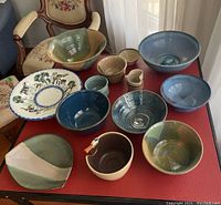 Photo of all pottery bowls arranged on a red tabletop showing variety and sizes