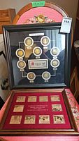 Two framed sets displayed together, upper frame with coins and lower frame with plaques