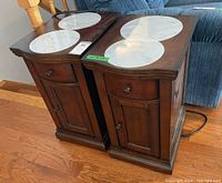 Two wooden side tables side by side showing brown finish and faux marble circular insets on tops.