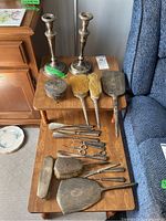 Overview of two candlesticks, round box, hand mirrors, brushes and manicure tools displayed on wooden table