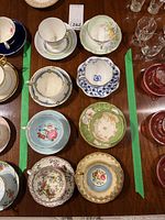 Top view of eight teacups arranged with matching saucers showing varied floral and decorative designs.