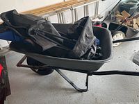 Full side view of the Erie wheelbarrow with metal frame and plastic bin showing its length and shape.