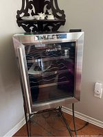Front view of the NewAir wine cooler showing stainless steel framed glass door and interior shelves.