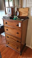 Full front view of the wood dresser showing four drawers with round knobs, glass top, and items on top.