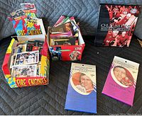 Lot of various trading cards organized in two open cardboard boxes and an Olympic Hockey Heroes storage box