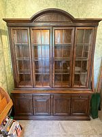 Front view of entire assembled two-piece wooden display cabinet with glass doors and lower storage.
