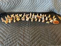 Wide view of all tea figures arranged on a padded surface showing variety of animal and human figures