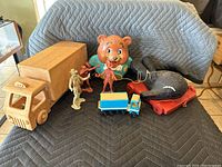 Overview photo of entire lot showing wooden truck, cowboy and Indian figures, bear bank, and whale toy.