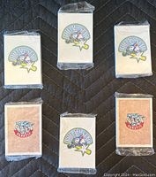 Front view of five unopened packs of The All Star Season 6 baseball cards arranged on a dark quilted surface. Three packs are white with the series logo, two are brown with the Fanatic logo.