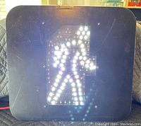 Pedestrian traffic signal showing white illuminated walking person figure.