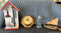 Full lot showing thermometer, barometer, glass jar, and sailboat model