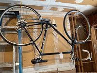 Blue Fuji men's road bicycle hanging with front and rear wheels attached, showing full frame and seat.