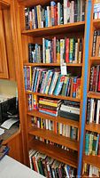 Books arranged on wooden bookshelves, mostly fiction and non-fiction titles covering diverse genres
