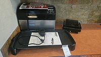 Black & Decker electric griddle with power cord and instruction manual underneath