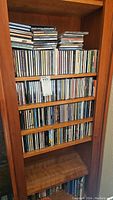 Wooden shelving unit holding multiple rows of music CDs