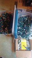 Overall photo of two large plastic bins filled with coiled multi-colored Christmas string lights and a box with accessories