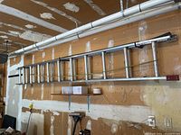 Full view of the extended aluminum ladder hanging horizontally on wall, showing length and construction.