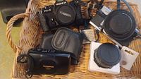 Basket with Olympus Stylus Zoom DLX camera, Yashica FX-3 camera, and lens attachments in cases
